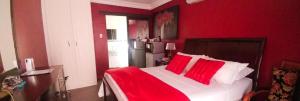 een rode slaapkamer met een groot bed met rode kussens bij Casadeross Guest House in Pretoria