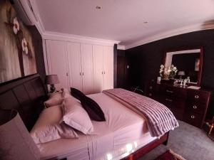 een slaapkamer met een groot bed met roze kussens bij Casadeross Guest House in Pretoria