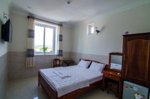 Schlafzimmer mit einem Bett, einem Fenster und einem TV in der Unterkunft Kim Hồng Anh Guest House in Phu Quoc