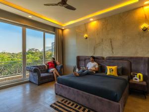 two people sitting on a bed in a room with a window at The Hosteller Bam Lonavala, Tiger Point in Lonavala