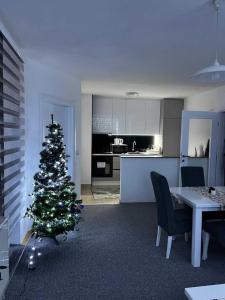a christmas tree in a living room with a kitchen at Apartman Nova Pale in Pale