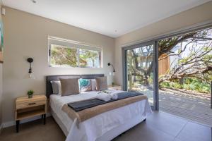 een slaapkamer met een bed en een groot raam bij Seagull View Sunset in Keurboomstrand