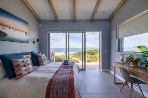 een slaapkamer met een groot bed met een groot raam bij Seagull View Sunset in Keurboomstrand