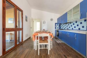 a blue and white kitchen with a table and chairs at AffittaSardegna - Appartamenti Appentos in Capo Comino