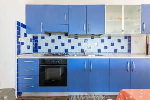 a blue kitchen with blue cabinets and a black oven at AffittaSardegna - Appartamenti Appentos in Capo Comino