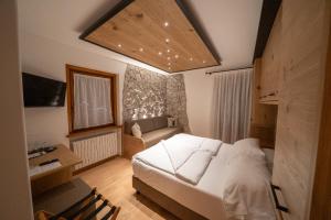 een slaapkamer met een wit bed en een bank bij HOTEL FONTANA in Sappada