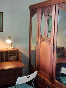 een houten kast met een bureau en een witte stoel bij Dombeya Ridge Guest Suite in Rustenburg