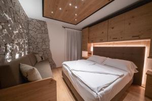 een slaapkamer met een bed en een stenen muur bij HOTEL FONTANA in Sappada
