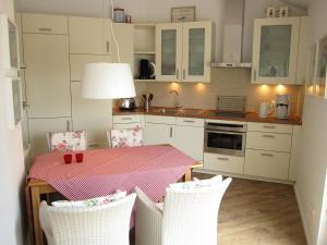una cucina con tavolo e sedie e una cucina con armadietti bianchi di Appartement Meeresrauschen a Baabe