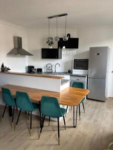 a kitchen with a wooden table and green chairs at Charming modern & bright apartment in Fontenay-sous-Bois
