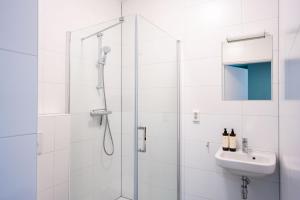 een witte badkamer met douche en wastafel bij Short Stay Wageningen in Wageningen