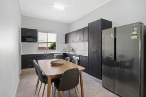 a kitchen with a table and a refrigerator at Edwin Cottage Dubbo - close to the hospital in Dubbo