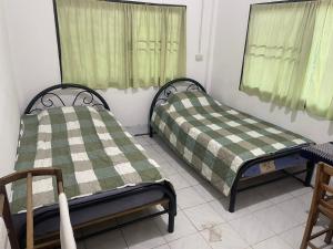 2 letti in una camera con tende verdi di Banpakan homestay 