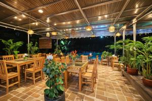 宁平Hidden Valley Eco Retreat Trang An的餐厅设有木桌、椅子和盆栽植物