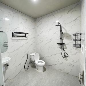a white bathroom with a toilet and a sink at Utama Lueng Bata Hotel in Luengbata