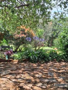 een tuin met bloemen en bomen en een stenen pad bij Dombeya Ridge Guest Suite in Rustenburg
