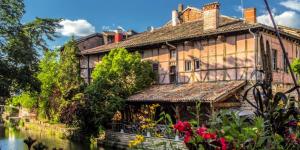 an old house next to a river with flowers at Appartement proche Paris, parking, centre-ville in Châtillon