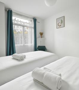 two beds in a white room with towels on them at Appartement proche Paris, parking, centre-ville in Châtillon
