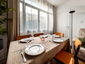 a wooden table with plates and wine glasses on it at Appartement proche Paris, parking, centre-ville in Châtillon