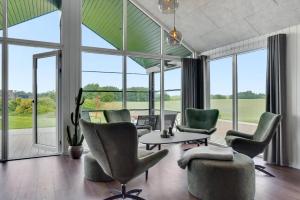ein Wohnzimmer mit Stühlen und einem Tisch und großen Fenstern in der Unterkunft Villavilla 546 in Vester Lem