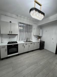 a kitchen with white cabinets and a chandelier at Apartament Vâlcea in Valcea