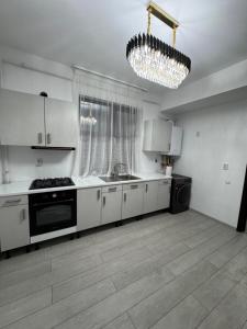 une cuisine avec des armoires blanches et un lustre dans l'établissement Apartament Modern Penthouse Rm Valcea, à Valcea