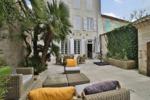un patio con mobili in vimini e palme e un edificio di La Bastide de Saint Martin a Saint-Martin-de-Ré