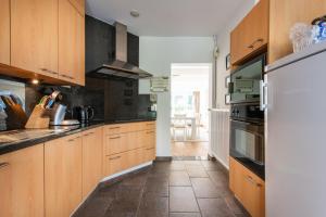 eine Küche mit Holzschränken und einem Kühlschrank in der Unterkunft Vakantiewoning Nungesser Coli in Koksijde