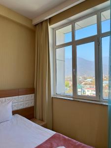 een slaapkamer met een bed en een groot raam bij Gabala Tufandag City Hotel in Gabala