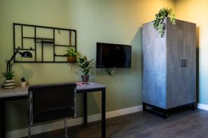 ein Zimmer mit einem Schreibtisch und einem Schrank mit einem Fernseher in der Unterkunft Short Stay Wageningen in Wageningen