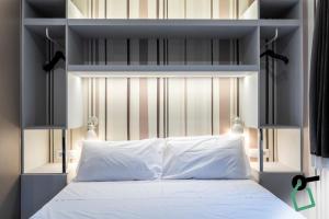 una camera da letto con un letto bianco con due luci sopra di Hotiday Bologna Arena a Bologna