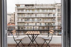 塞萨洛尼基Restored, immaculate condo @ historic center #1的阳台配有桌椅,与大楼相连