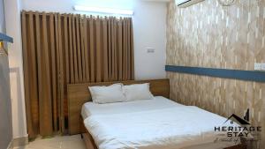 a small bedroom with a bed with white sheets and pillows at Heritage Stay Bagerhat in Bāgherhāt