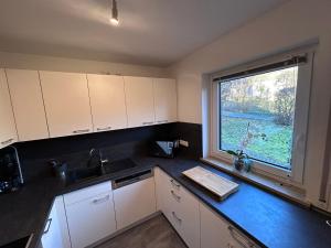 a kitchen with white cabinets and a large window at Wagner Apartment Bayreuth FeWo - Erdgeschoss - nähe Festspielhaus - Free-WiFi - Schlafzimmer - Boxspringbetten - große Küche - Dusche - Badewanne - extra WC - Terrasse - DTV-Zertifiziert in Bayreuth