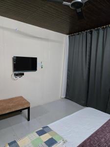 a bedroom with a bed and a flat screen tv at Shyam Resort in Khandwa