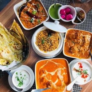 a table with many different dishes of food on it at Prestige Palace in Mugad