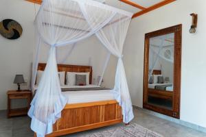 a bedroom with a canopy bed with a mirror at Changarawe Hotel & Retreat in Pongwe