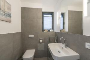 ein Badezimmer mit Waschbecken, Toilette und Spiegel in der Unterkunft Ferienhaus am See LEE - Vogteihof am Bodden in Streu