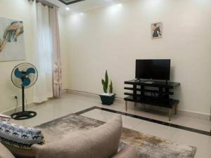 un salon avec un canapé et une télévision à écran plat dans l'établissement Anyiese Homes and Getaways, à Kampala 2 autres photos