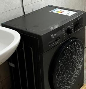 een zwarte wasmachine in een badkamer naast een wastafel bij DK Homes in Bunamwaya