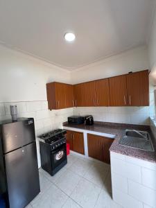 een keuken met houten kasten en een roestvrijstalen koelkast bij DK Homes in Bunamwaya