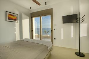 een witte slaapkamer met een bed en een groot raam bij Eosea Selene in Ierissos