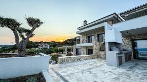 een groot wit huis met een zonsondergang op de achtergrond bij Eosea Selene in Ierissos