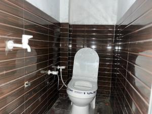 a bathroom with a toilet in a brown tiled wall at Prime Hotel in Kannauj