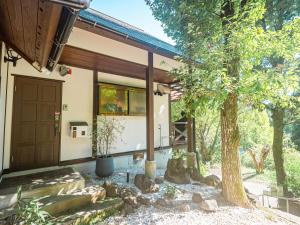 een huis met een houten deur en een boom bij Kurokawa Mori No Kiki in Minamioguni