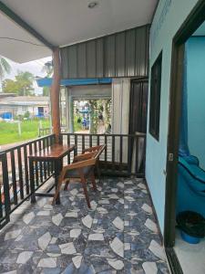 een veranda met een bank en een tafel op een balkon bij KohmookLuckyfamily in Ban Chao Mai