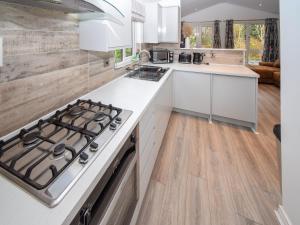 une cuisine avec des comptoirs blancs et une cuisinière dans l'établissement Bluebird Lodge 2 - Uk50932, à High Nibthwaite