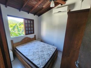 a small bedroom with a bed and a window at Casablanca do Rosa in Praia do Rosa