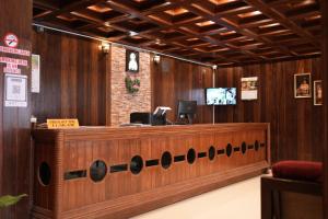 una hall con un bancone della reception in legno con una TV di Thekkady Arasi Hotel a Thekkady