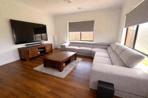 ein Wohnzimmer mit Sofa und Flachbildfernseher in der Unterkunft Spacious 5BDR Family Haven in Melbourne in Werribee